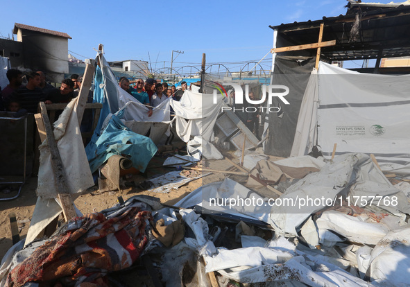 Palestinians inspect the site of an Israeli strike on a tent housing displaced people at Al-Aqsa Martyrs Hospital in Deir Al-Balah, in the c...