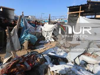 Palestinians inspect the site of an Israeli strike on a tent housing displaced people at Al-Aqsa Martyrs Hospital in Deir Al-Balah, in the c...