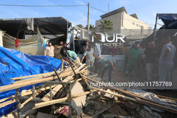 Palestinians inspect the site of an Israeli strike on a tent housing displaced people at Al-Aqsa Martyrs Hospital in Deir Al-Balah, in the c...