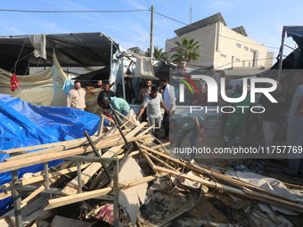 Palestinians inspect the site of an Israeli strike on a tent housing displaced people at Al-Aqsa Martyrs Hospital in Deir Al-Balah, in the c...