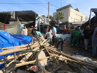 Palestinians inspect the site of an Israeli strike on a tent housing displaced people at Al-Aqsa Martyrs Hospital in Deir Al-Balah, in the c...