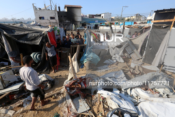 Palestinians inspect the site of an Israeli strike on a tent housing displaced people at Al-Aqsa Martyrs Hospital in Deir Al-Balah, in the c...