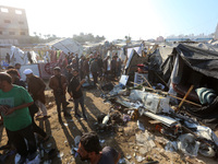 Palestinians inspect the site of an Israeli strike on a tent housing displaced people at Al-Aqsa Martyrs Hospital in Deir Al-Balah, in the c...