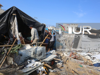 Palestinians inspect the site of an Israeli strike on a tent housing displaced people at Al-Aqsa Martyrs Hospital in Deir Al-Balah, in the c...