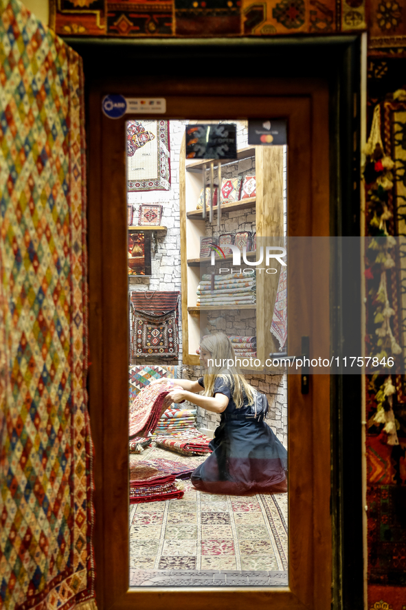 A woman browse Azeri carpets in a carper shop in an Old Town of Baku, Azerbaijan on November 9, 2024. 