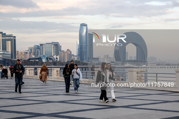 People walk on Caspian Sea Boulevard in Baku in front of landmark architecture, Azerbaijan on November 9, 2024. 