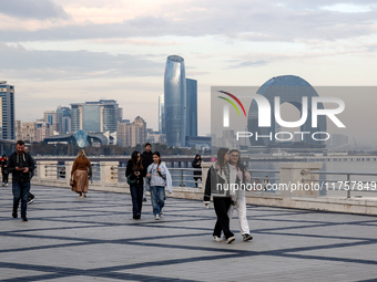 People walk on Caspian Sea Boulevard in Baku in front of landmark architecture, Azerbaijan on November 9, 2024. (