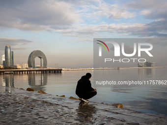 A man sits on Caspian Sea Boulevard in Baku in front of landmark architecture, Azerbaijan on November 9, 2024. (