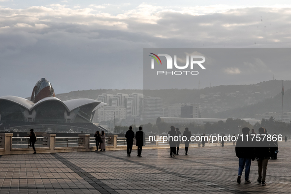 People walk on Caspian Sea Boulevard in Baku in front of landmark architecture, Azerbaijan on November 9, 2024. 