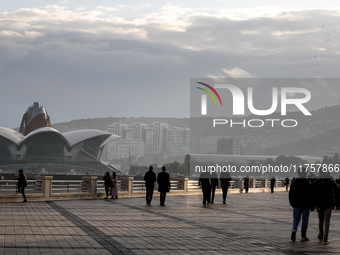 People walk on Caspian Sea Boulevard in Baku in front of landmark architecture, Azerbaijan on November 9, 2024. (