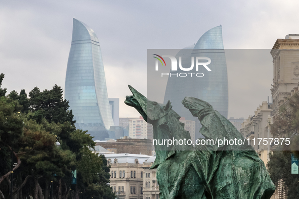 Flame towers are seen from a distance with older part of city and modern sculpture in front in Baku, Azerbaijan on November 9, 2024. 