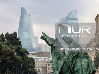 Flame towers are seen from a distance with older part of city and modern sculpture in front in Baku, Azerbaijan on November 9, 2024. (