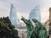 Flame towers are seen from a distance with older part of city and modern sculpture in front in Baku, Azerbaijan on November 9, 2024. (