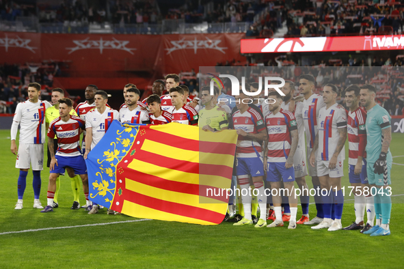 Players pose with the Valencia flag due to the floods after a DANA storm on October 29 during the LaLiga Hypermotion match between Granada C...