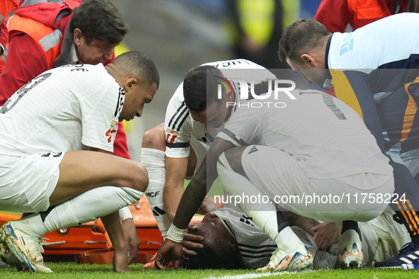 Eder Militao centre-back of Real Madrid and Brazil dejected after his injury is consoled by his teammates during the La Liga match between R...