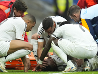 Eder Militao centre-back of Real Madrid and Brazil dejected after his injury is consoled by his teammates during the La Liga match between R...