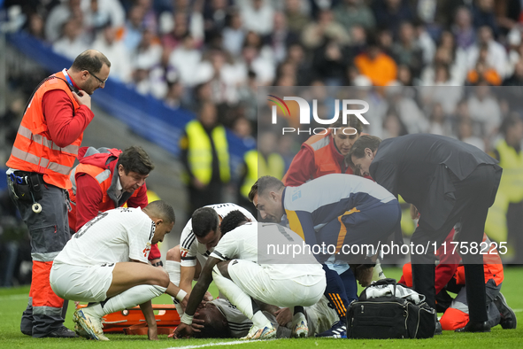 Eder Militao centre-back of Real Madrid and Brazil dejected after his injury is consoled by his teammates during the La Liga match between R...