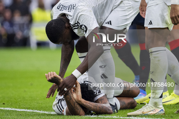 Eder Militao of Real Madrid CF is injured on the ground and is helped by his teammate Antonio Rudiger of Real Madrid CF during the La Liga E...