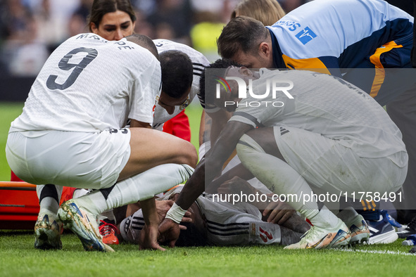 Eder Militao of Real Madrid CF (center) is injured on the ground, surrounded by his teammates (from left to right) Lucas Vazquez, Kylian Mba...