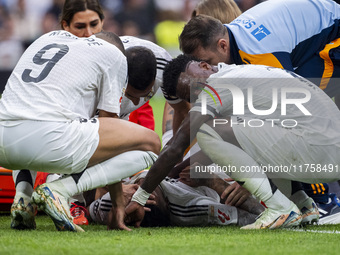 Eder Militao of Real Madrid CF (center) is injured on the ground, surrounded by his teammates (from left to right) Lucas Vazquez, Kylian Mba...