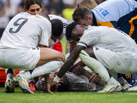 Eder Militao of Real Madrid CF (center) is injured on the ground, surrounded by his teammates (from left to right) Lucas Vazquez, Kylian Mba...