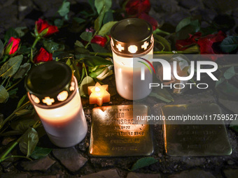 Candles and flowers are seen by stumbling stones (Stolpersteine) commemorating victims of Holocaust, during the 65th anniversary of Kristall...