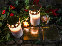 Candles and flowers are seen by stumbling stones (Stolpersteine) commemorating victims of Holocaust, during the 65th anniversary of Kristall...