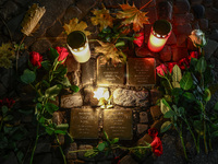 Candles and flowers are seen by stumbling stones (Stolpersteine) commemorating victims of Holocaust, during the 65th anniversary of Kristall...