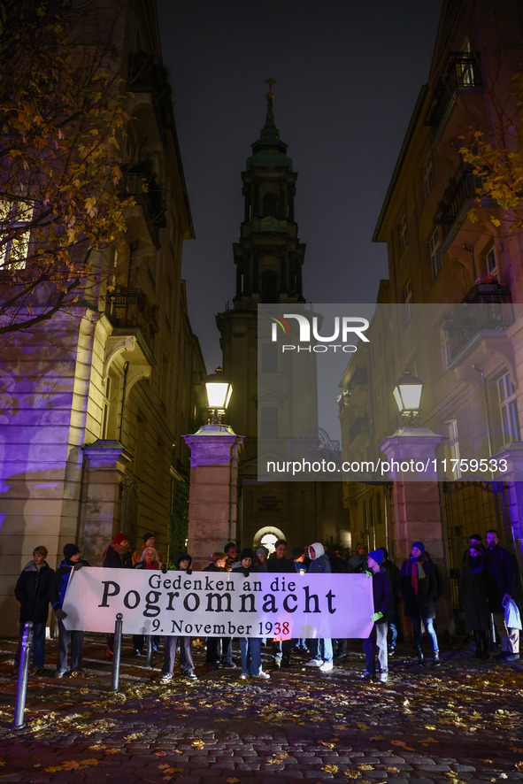 People stand in front of the Sophienkirche while attending a march commemorating the 65th anniversary of the Night of Broken Glass (Kristall...