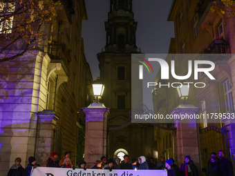 People stand in front of the Sophienkirche while attending a march commemorating the 65th anniversary of the Night of Broken Glass (Kristall...