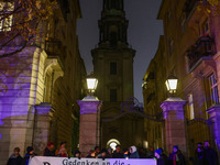 People stand in front of the Sophienkirche while attending a march commemorating the 65th anniversary of the Night of Broken Glass (Kristall...