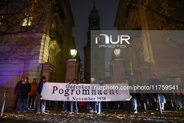 People stand in front of the Sophienkirche while attending a march commemorating the 65th anniversary of the Night of Broken Glass (Kristall...