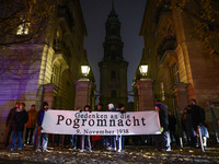 People stand in front of the Sophienkirche while attending a march commemorating the 65th anniversary of the Night of Broken Glass (Kristall...