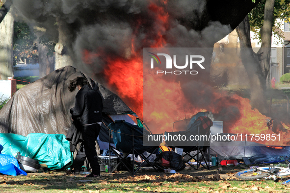 A person tries to recover belongings from a fire that engulfs tents at a homeless encampment in Gage Park, in Hamilton, Ontario, on November...