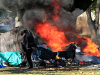 A person tries to recover belongings from a fire that engulfs tents at a homeless encampment in Gage Park, in Hamilton, Ontario, on November...