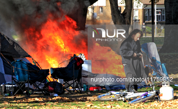 A person tries to recover belongings from a fire that engulfs tents at a homeless encampment in Gage Park, in Hamilton, Ontario, on November...