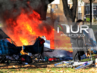 A person tries to recover belongings from a fire that engulfs tents at a homeless encampment in Gage Park, in Hamilton, Ontario, on November...