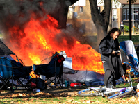 A person tries to recover belongings from a fire that engulfs tents at a homeless encampment in Gage Park, in Hamilton, Ontario, on November...