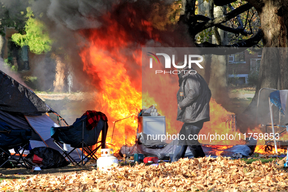 A person tries to recover belongings from a fire that engulfs tents at a homeless encampment in Gage Park, in Hamilton, Ontario, on November...