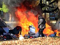 A person tries to recover belongings from a fire that engulfs tents at a homeless encampment in Gage Park, in Hamilton, Ontario, on November...