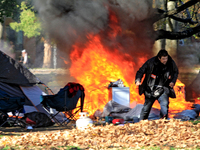 A person tries to recover belongings from a fire that engulfs tents at a homeless encampment in Gage Park, in Hamilton, Ontario, on November...