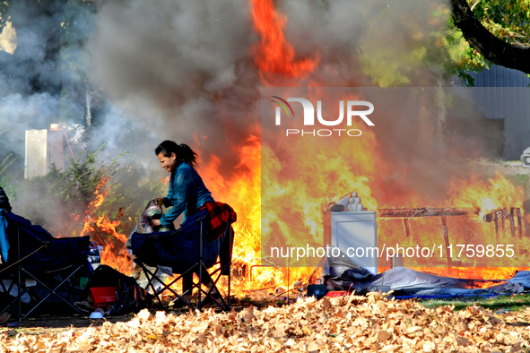 A person tries to recover belongings from a fire that engulfs tents at a homeless encampment in Gage Park, in Hamilton, Ontario, on November...