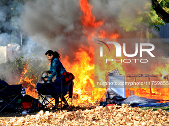 A person tries to recover belongings from a fire that engulfs tents at a homeless encampment in Gage Park, in Hamilton, Ontario, on November...