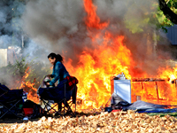 A person tries to recover belongings from a fire that engulfs tents at a homeless encampment in Gage Park, in Hamilton, Ontario, on November...