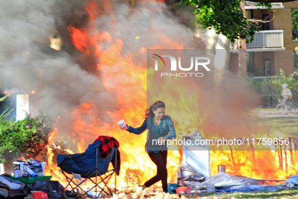 A person escapes from a fire that engulfs tents at a homeless encampment in Gage Park, in Hamilton, Ontario, on November 9, 2024. No injurie...