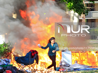 A person escapes from a fire that engulfs tents at a homeless encampment in Gage Park, in Hamilton, Ontario, on November 9, 2024. No injurie...