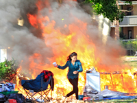 A person escapes from a fire that engulfs tents at a homeless encampment in Gage Park, in Hamilton, Ontario, on November 9, 2024. No injurie...