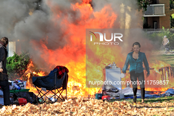 A person tries to recover belongings from a fire that engulfs tents at a homeless encampment in Gage Park, in Hamilton, Ontario, on November...