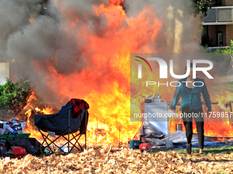 A person tries to recover belongings from a fire that engulfs tents at a homeless encampment in Gage Park, in Hamilton, Ontario, on November...