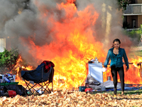 A person tries to recover belongings from a fire that engulfs tents at a homeless encampment in Gage Park, in Hamilton, Ontario, on November...